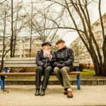 Elderly couple happily sitting on a bench together.